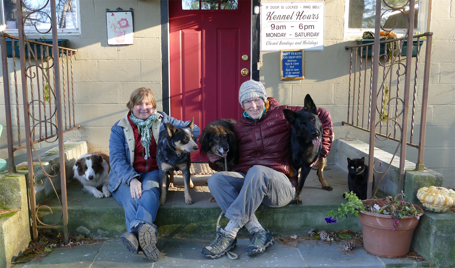photo of Anne Reagan and Liz Quinn and their dogs and cat in front of Albanhaus Kennel door